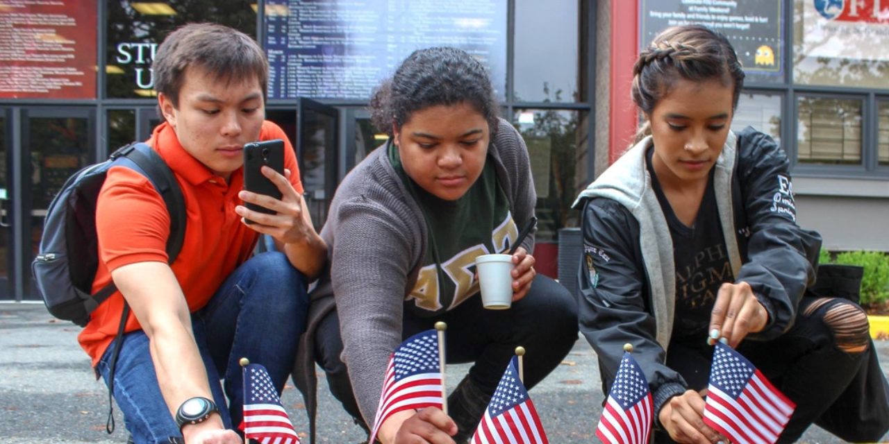 Students stick small American flags in the ground.