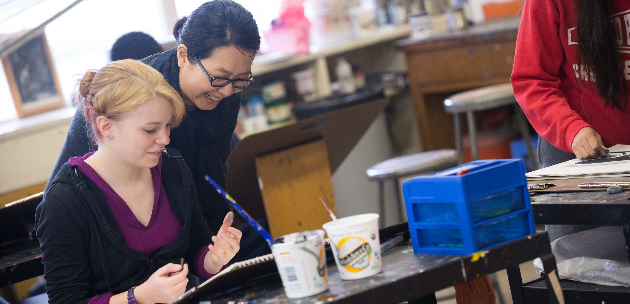 Instructor helping student in art class.