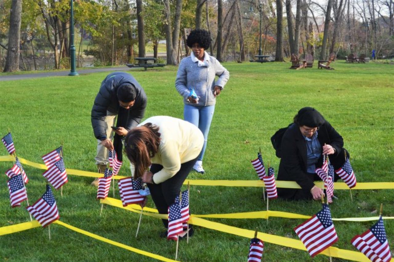 Metropolitan Campus Veterans Day ceremony attendees plant flags to honor veterans.