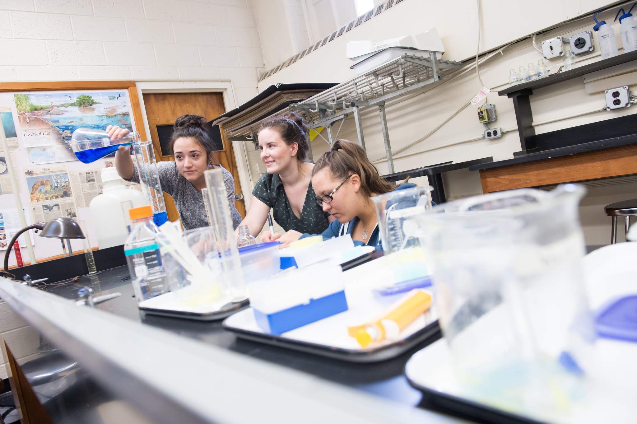 Three students conduct science research in a lab.