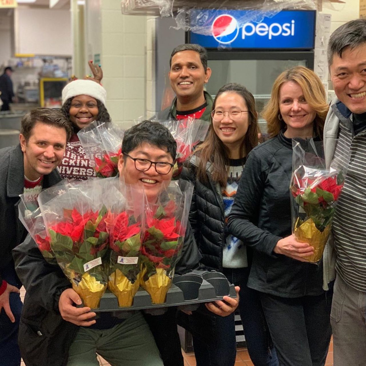 A group of students pose for a photo while holding poinsettias.