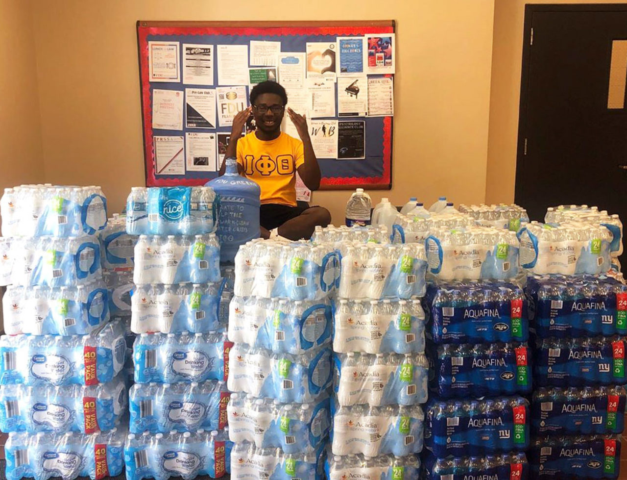 A student sits in front of mountains of bottled water cases.