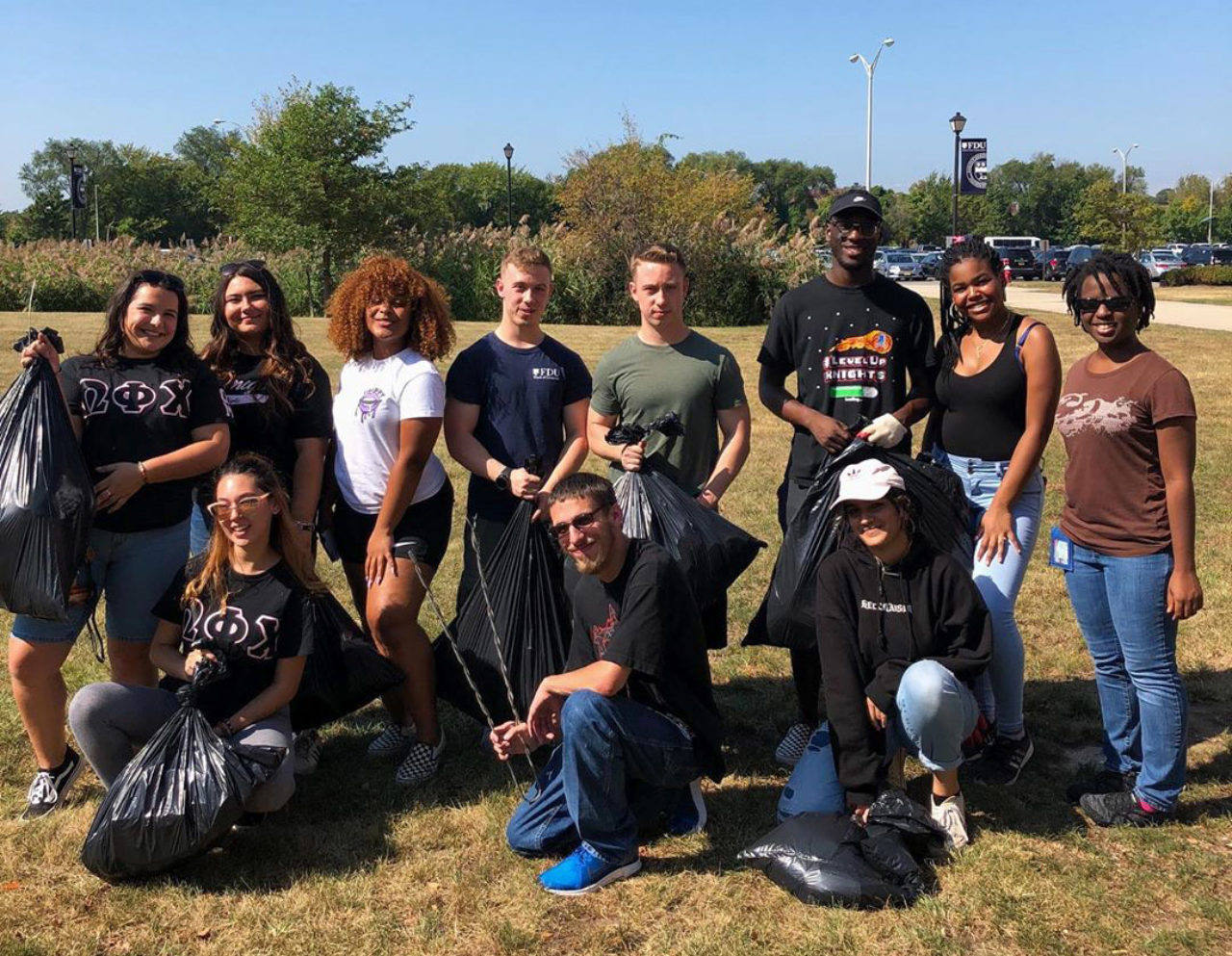 A group of students holding garbage bags pose for a photo.