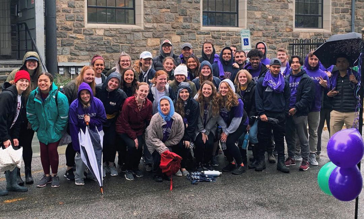 A group of students pose for a photo wearing matching purple shirts.