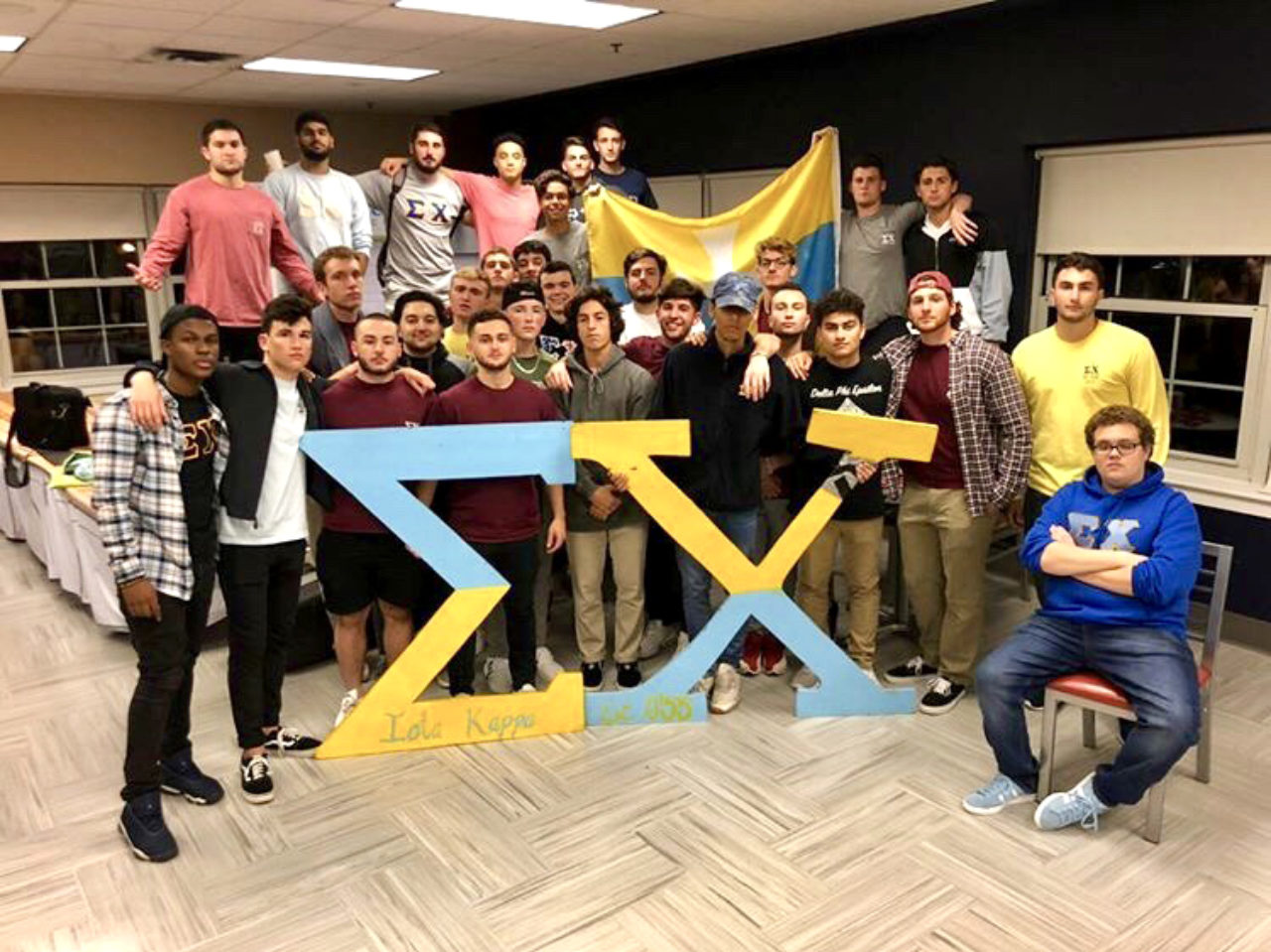 Group photo of Sigma Chi brothers in front of "Sigma" "Chi" greek letters.