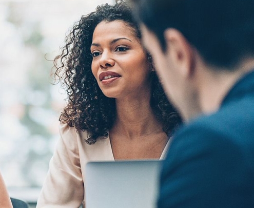 three women and one man working and talking together in a conference room setting