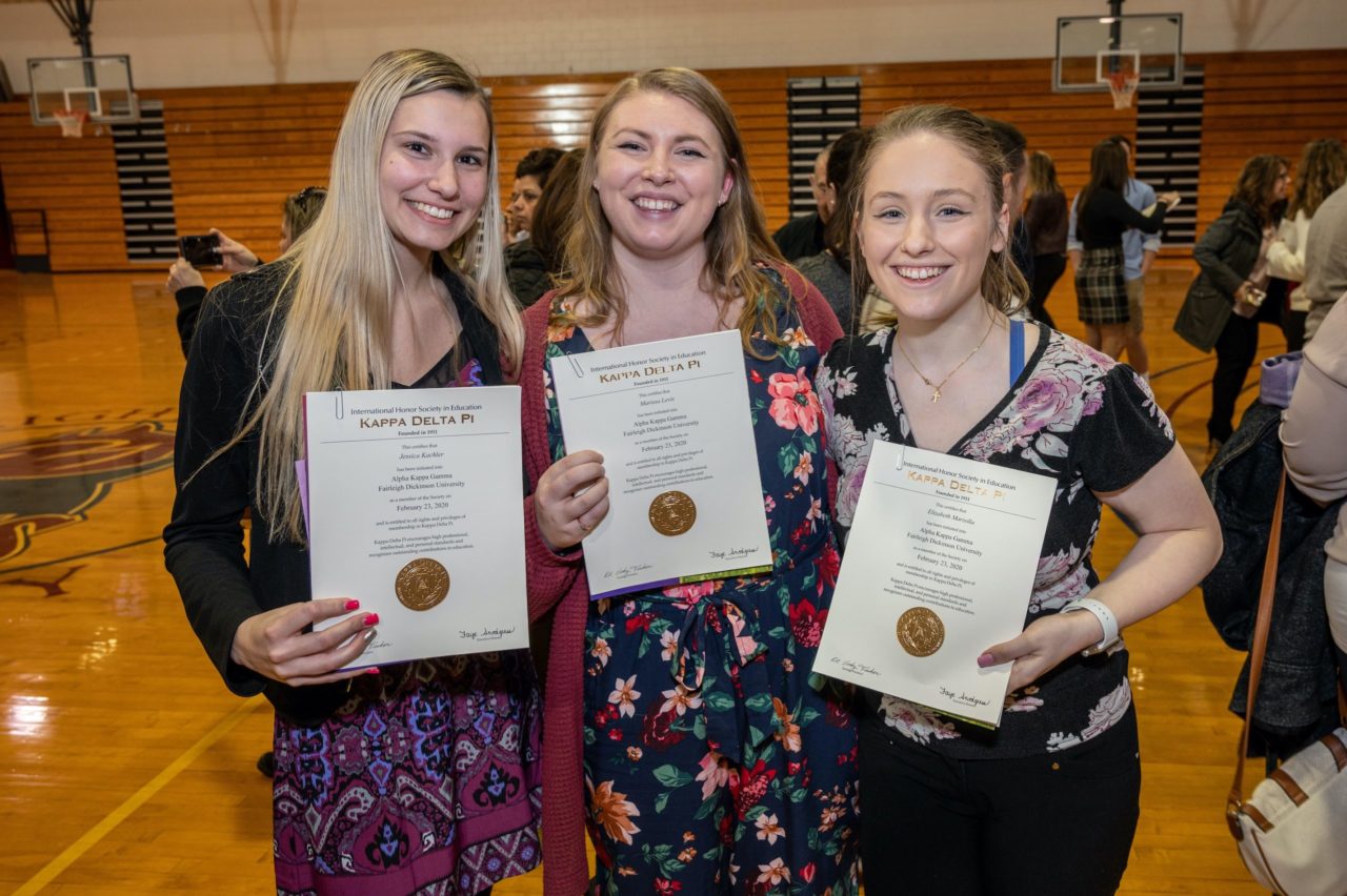 Three female students stand side by side and hold their Kappa Delta Pi certificates.