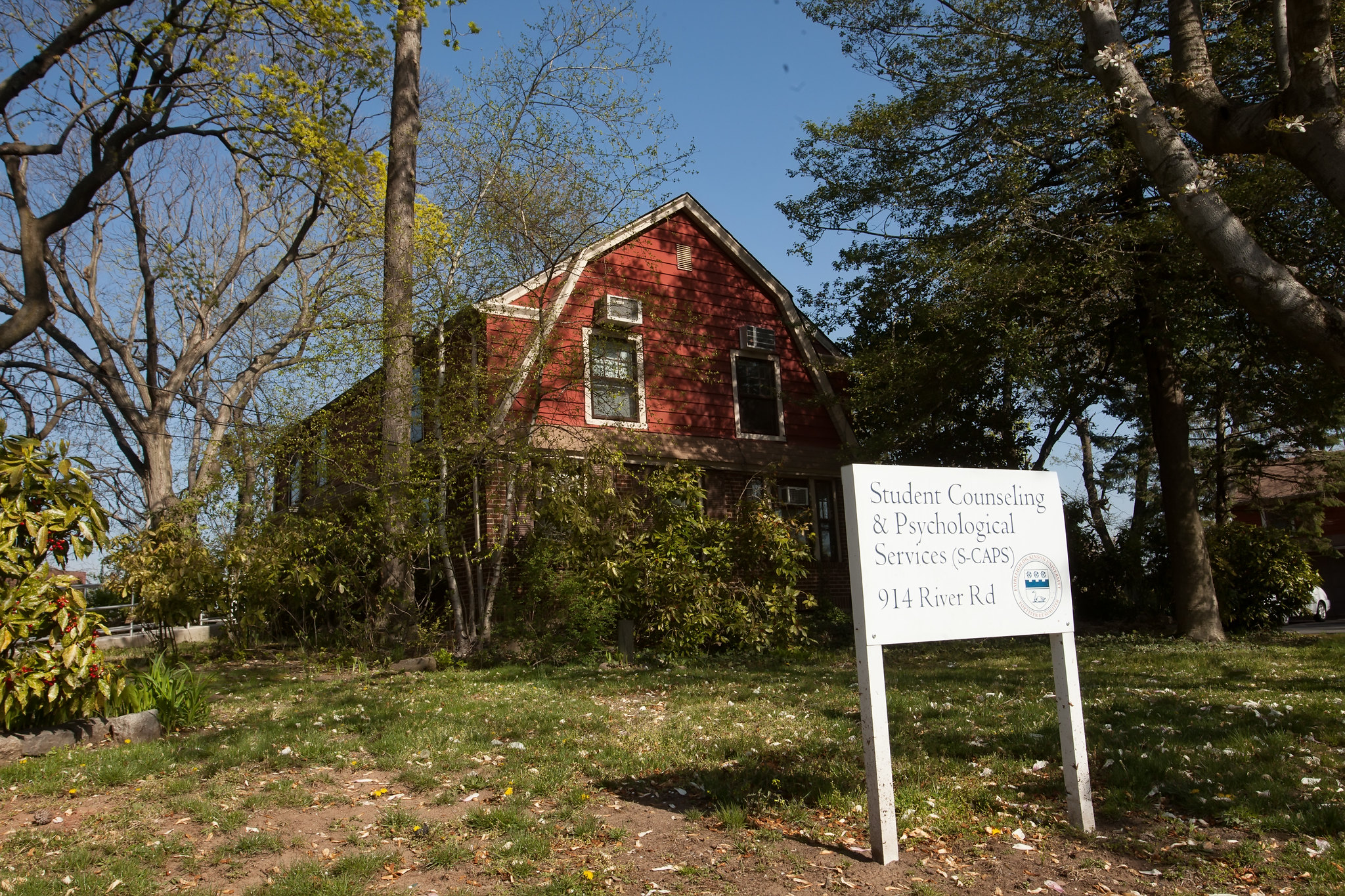 A building behind foliage, with a sign in front of it.