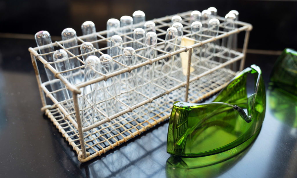 Lab equipment, including test tubes and safety googles sit on a table.