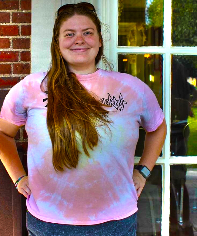 A young woman stands outside.