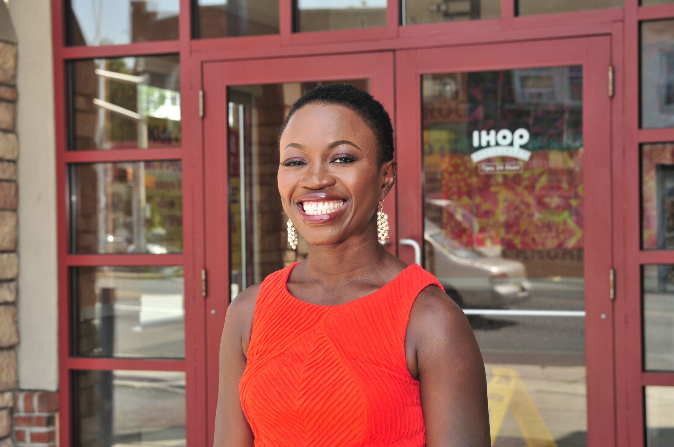 A young woman stands outside of an IHOP restaurant.