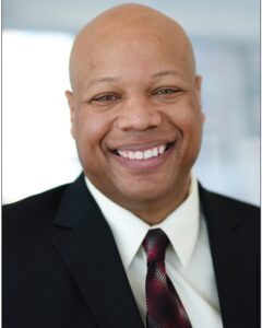 A professional headshot of a man wearing a suit