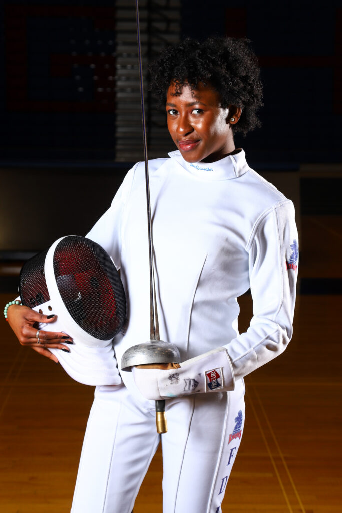 A portrait of Natalia Toby in her fencing gear with her epee sword. 