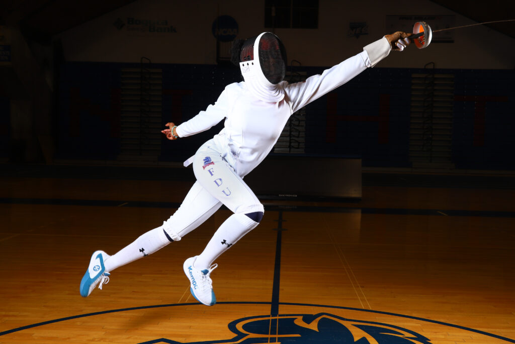 Natalia Toby in an action pose wearing her fencing uniform and using her epee sword. 