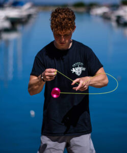 Kevin Weller shows off his impressive yo-yo skills in front of a lake. 