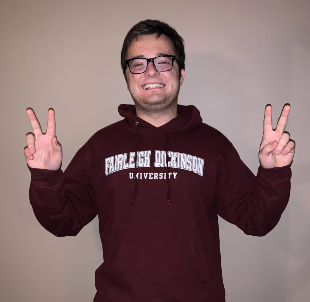 A young man in an FDU sweatshirt gives double peace signs.