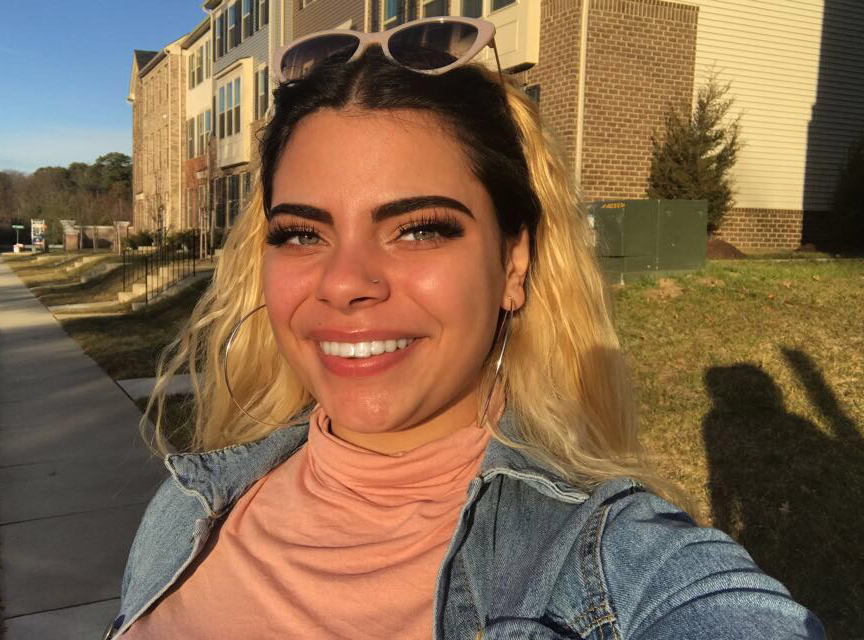A selfie of a young woman standing outside.