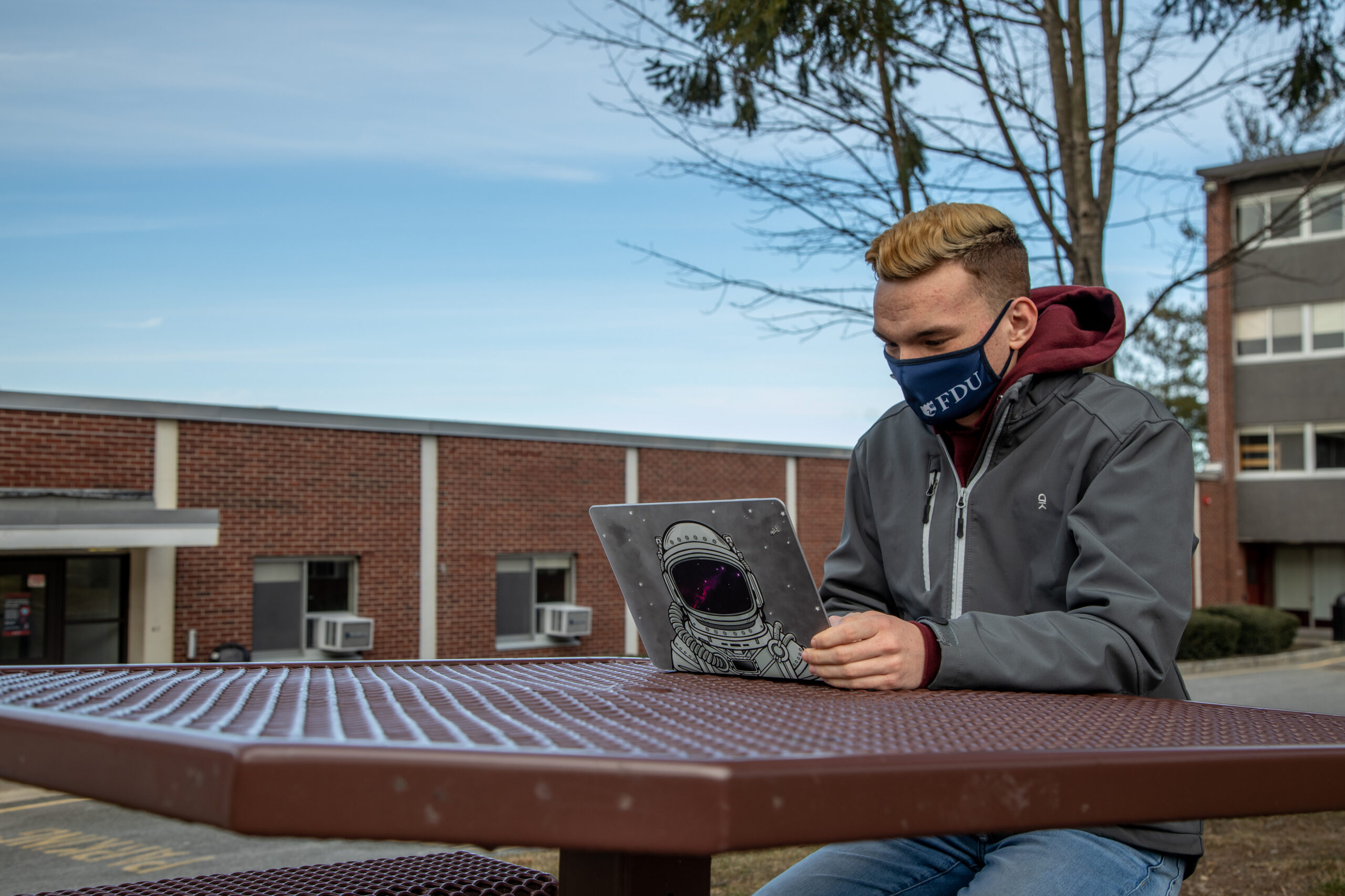 A student works on a laptop wearing an FDU mask.