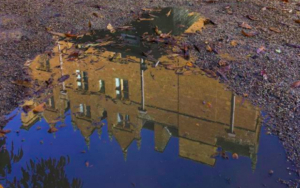 A puddle clearly reflects an image of Wroxton Abbey.