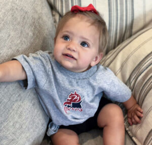 A baby wears an FDU Devils athletics shirt.