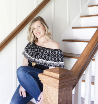 A woman sits on a wooden staircase.