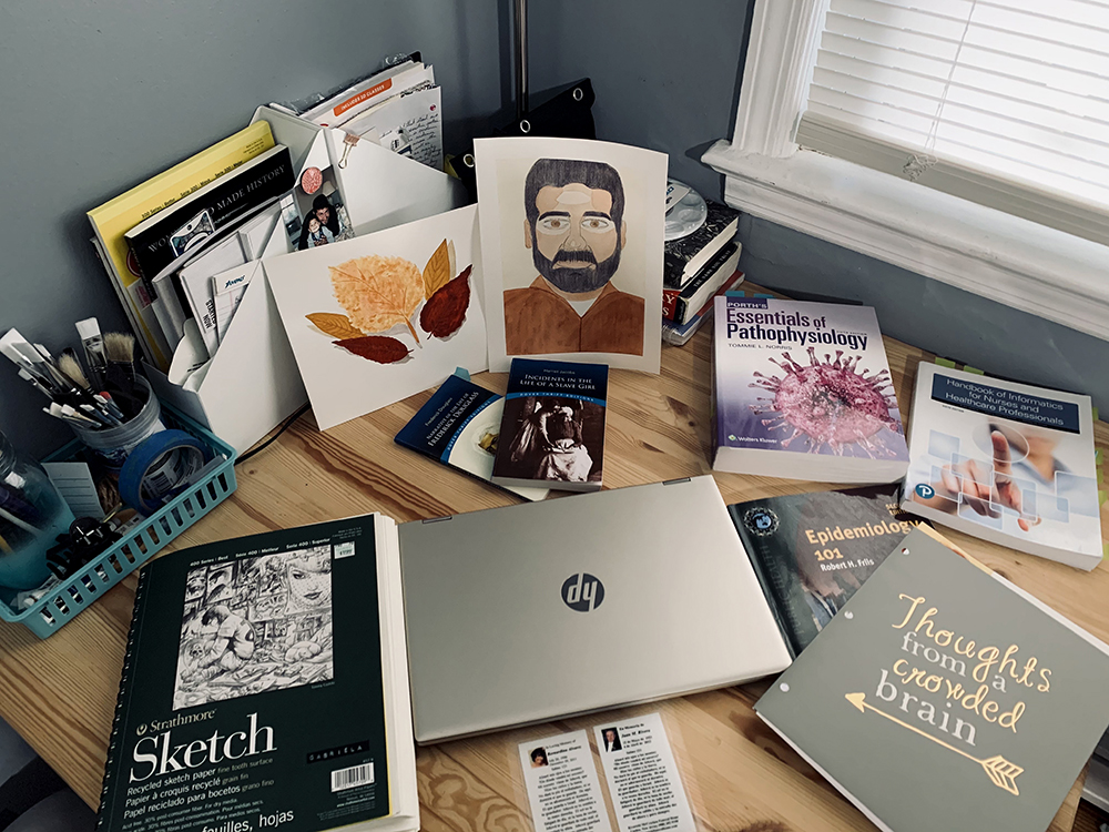 Textbooks, art supplies and a laptop adorn a student desk.