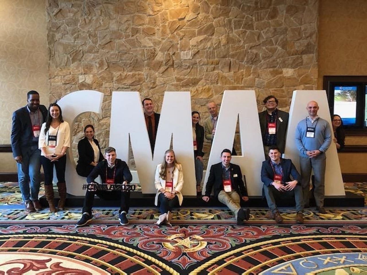 FDU CMAA members pose in front of letters that spell "CMAA."