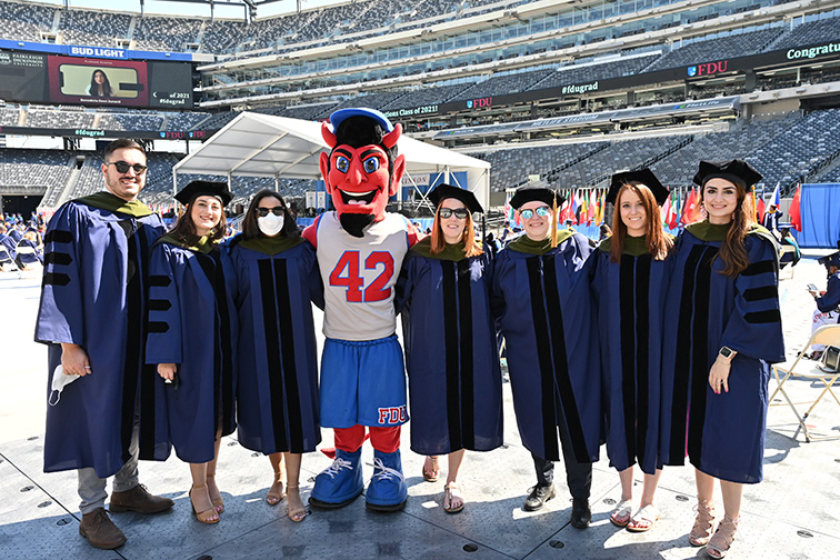 Graduates strike a pose with Ian the Devil, the Florham Campus mascot.