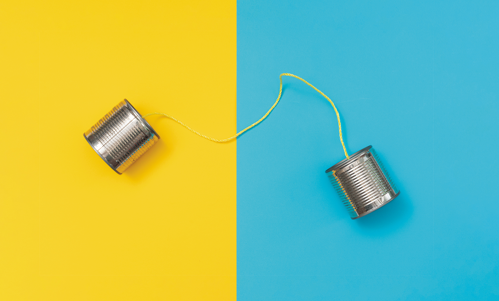 Tin can phone on yellow and blue paper backgrounds.