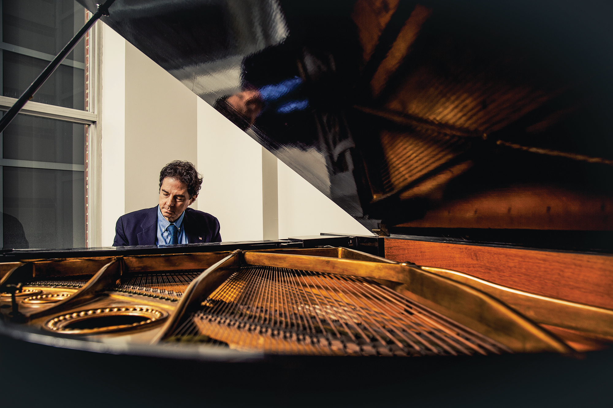 A man plays the piano wearing a suit.