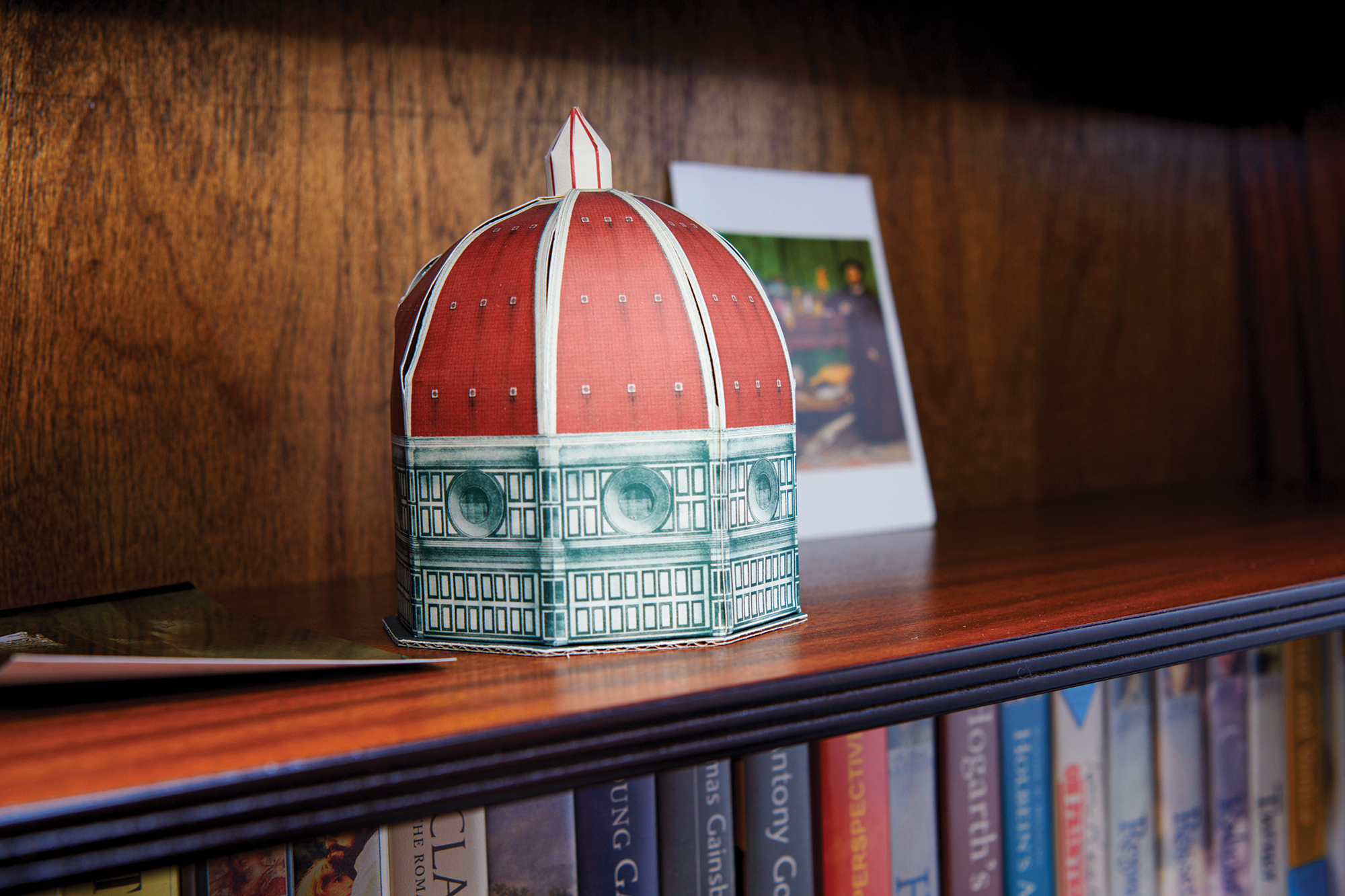 A miniature cardboard mock of the Duomo in Florence, Italy, sits on a bookshelf.