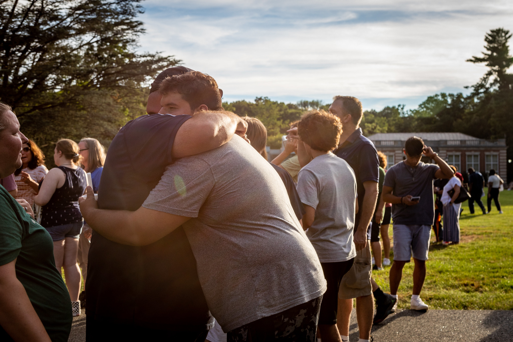 Families and students hug at a candlelight ceremony.
