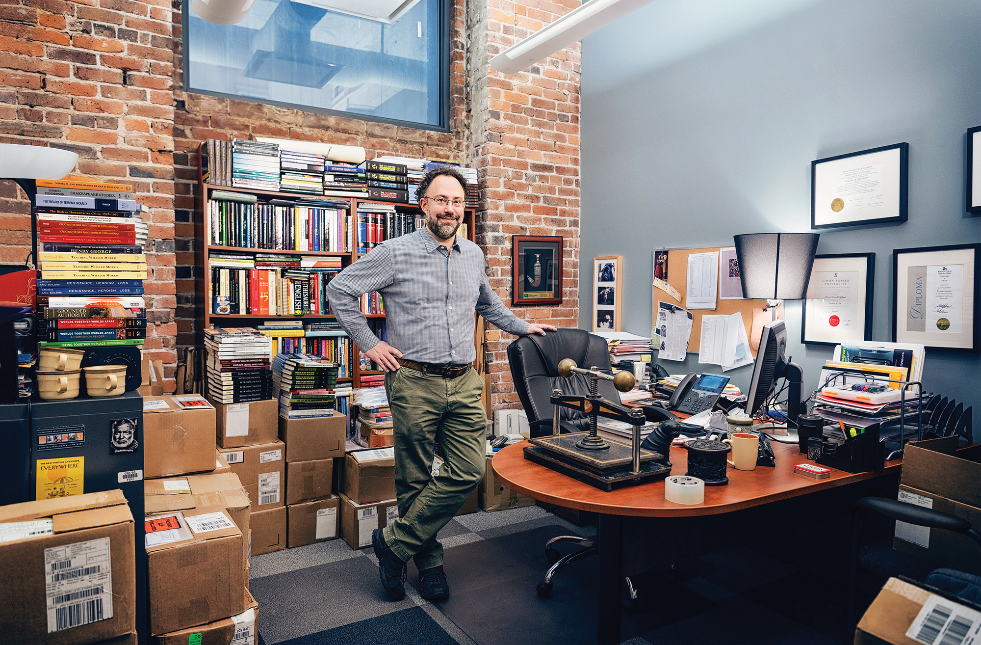 A male professor stands in his cluttered office.