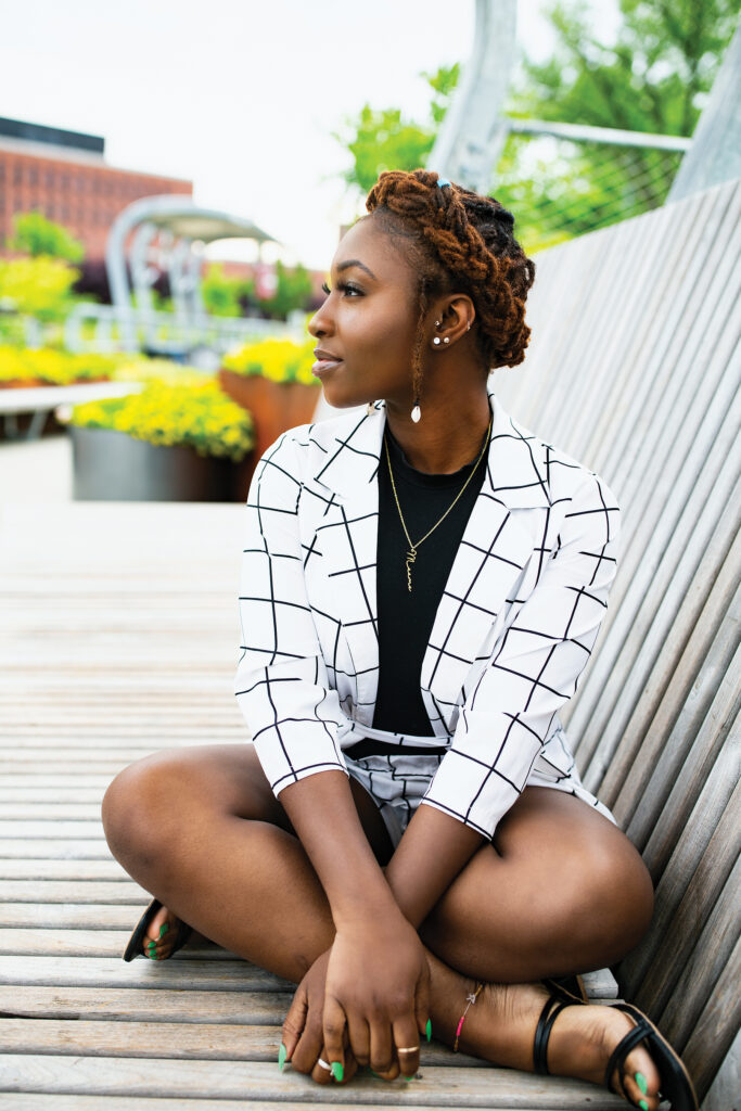 A young Black woman sits cross-legged on the Metro footbridge.