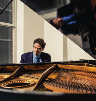 A man plays the piano wearing a suit.