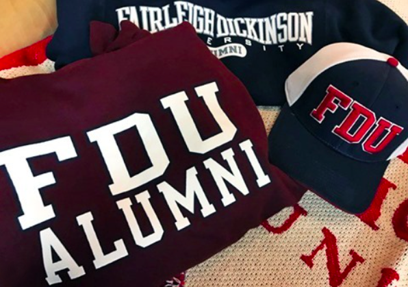 A pile of FDU alumni gear: a sweatshirt and hat and t-shirt.