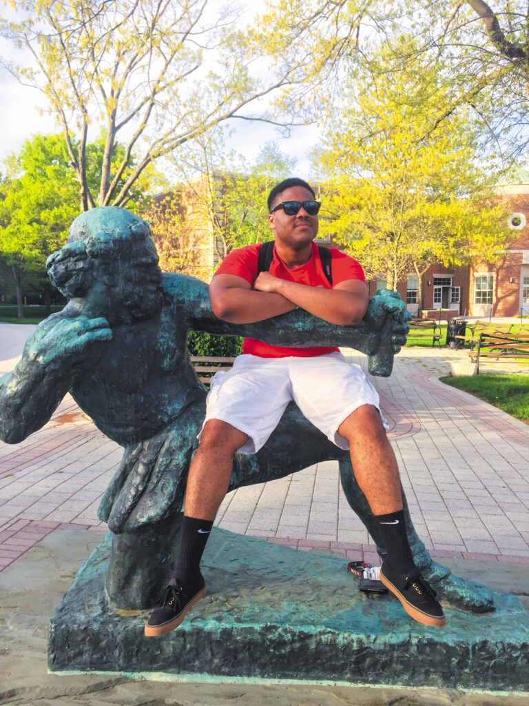 A young man sits on the Ulysses statue.