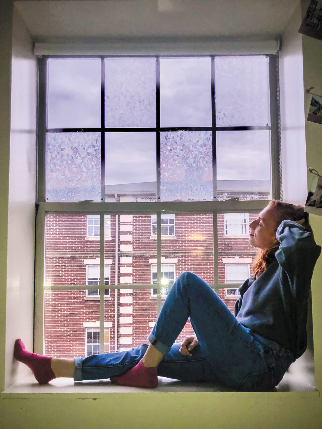 A young woman sprawls in a window seat, taking a rest between classes.