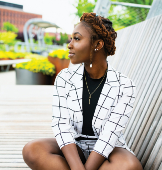 A young Black woman sits cross-legged on the Metro footbridge.