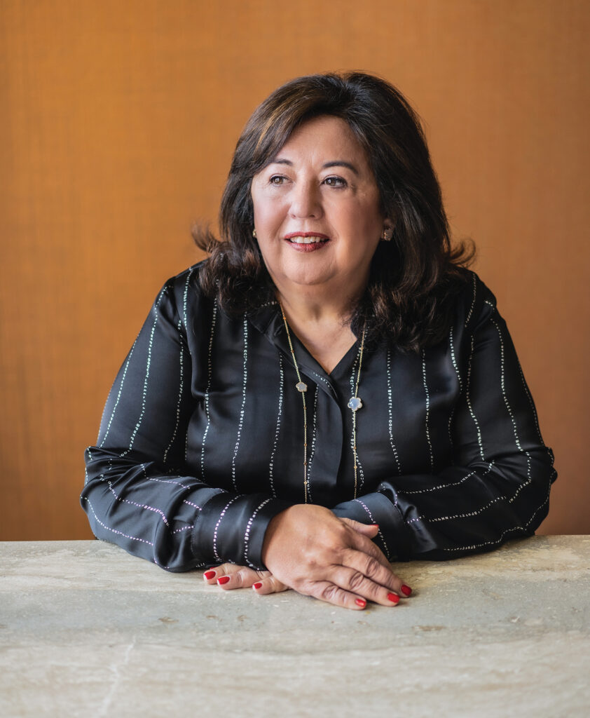 A professional portrait of a businesswoman sitting at a table.