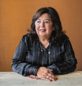 A professional portrait of a businesswoman sitting at a table.