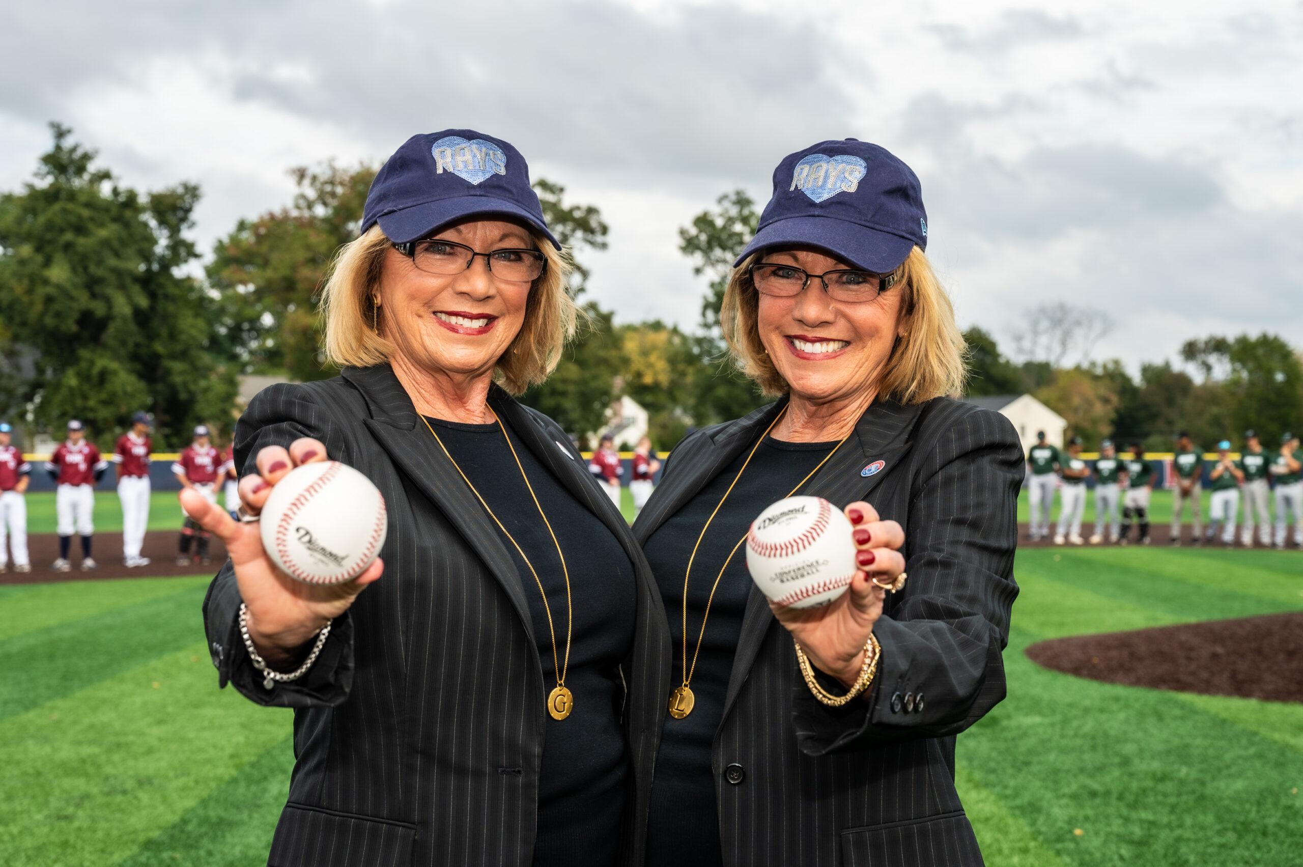 Two women hold baseballs.