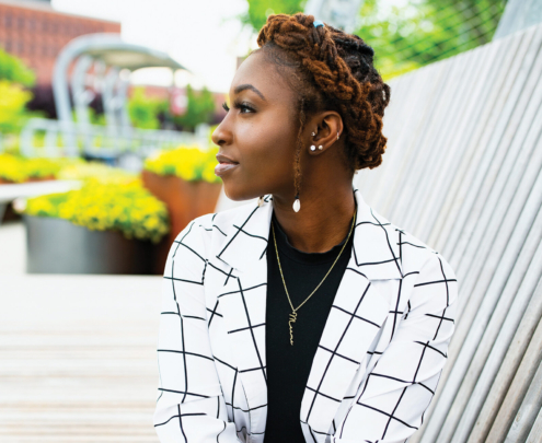 A young Black woman sits cross-legged on the Metro footbridge.