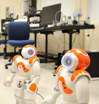 Robots in an engineering lab, with computer stations in the background.