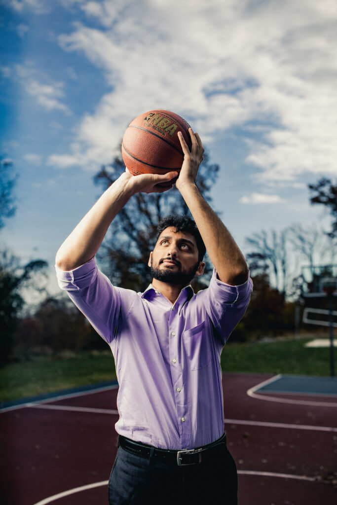 Nikhil Sharma preps to shoot a basketball on an outdoor basketball court.