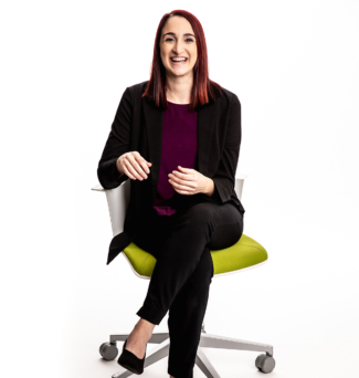 Portrait of a woman sitting on a desk chair and smiling.
