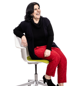 Portrait of a woman sitting in a desk chair, with an open and inviting stance.