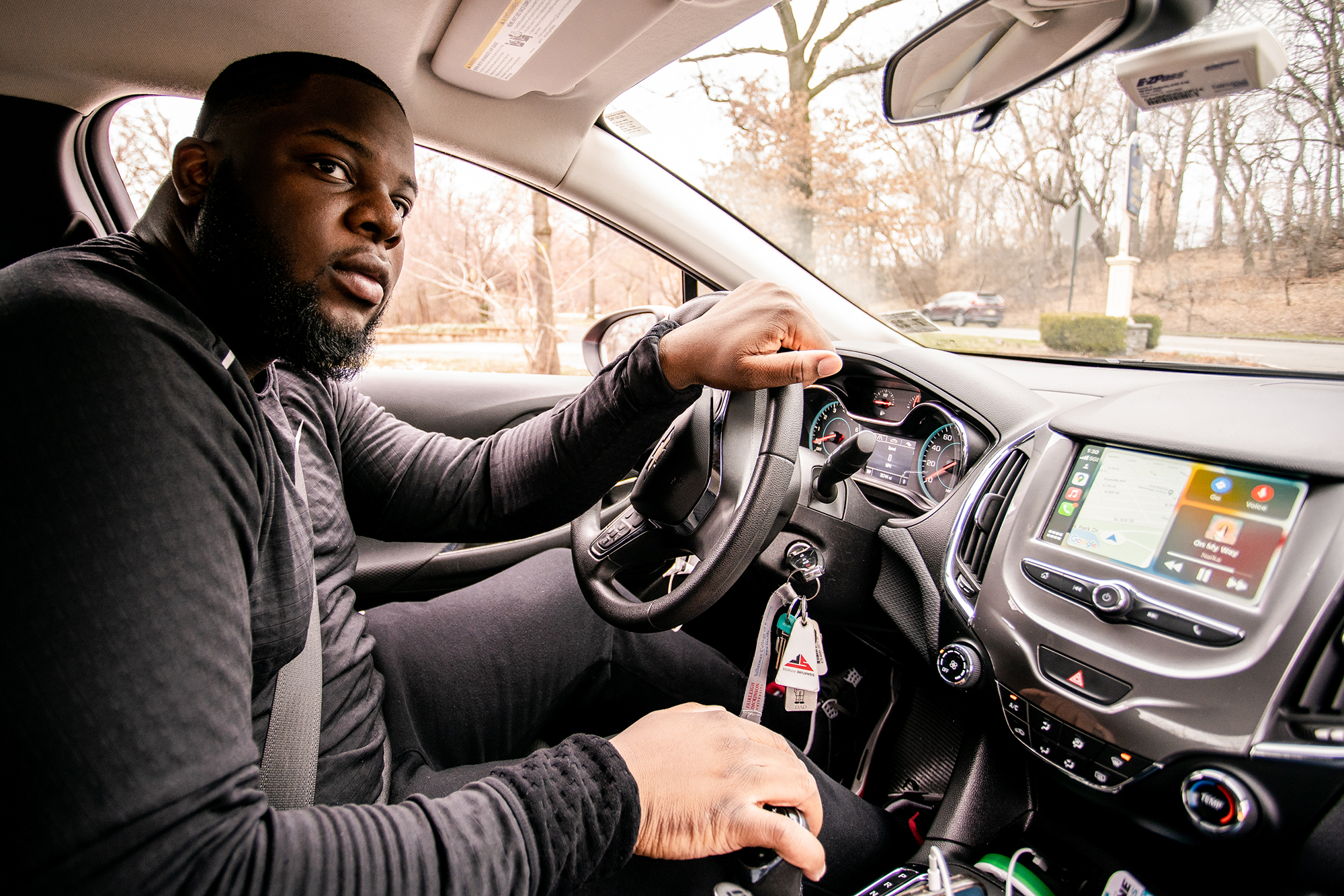 A young man sits in the driver's seat, holding the steering wheel.