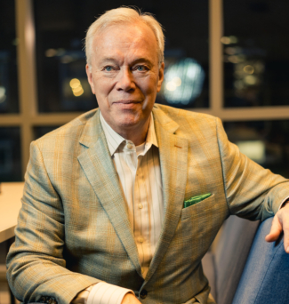 Portrait of a man in a suit, sitting on a chair.