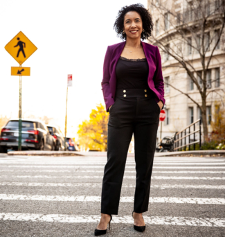 A woman poses for a photo in the crosswalk on a street in New York City.